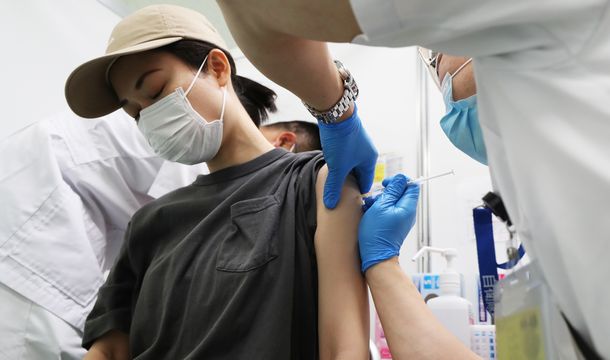 写真・図版 : 新型コロナウイルスのワクチン接種対象年齢が64歳以下に引き下げられた自衛隊大規模接種センターで、接種を受ける女性＝2021年6月17日、東京都千代田区