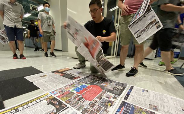 写真・図版 : 「リンゴ日報」最後の朝刊が刷り上がったあと、本社編集局の床に新聞を広げる記者ら。創刊から２６年の歴史が刻まれた紙面を記憶に残すため、みなで写真を撮るのだという＝2021年6月24日、香港