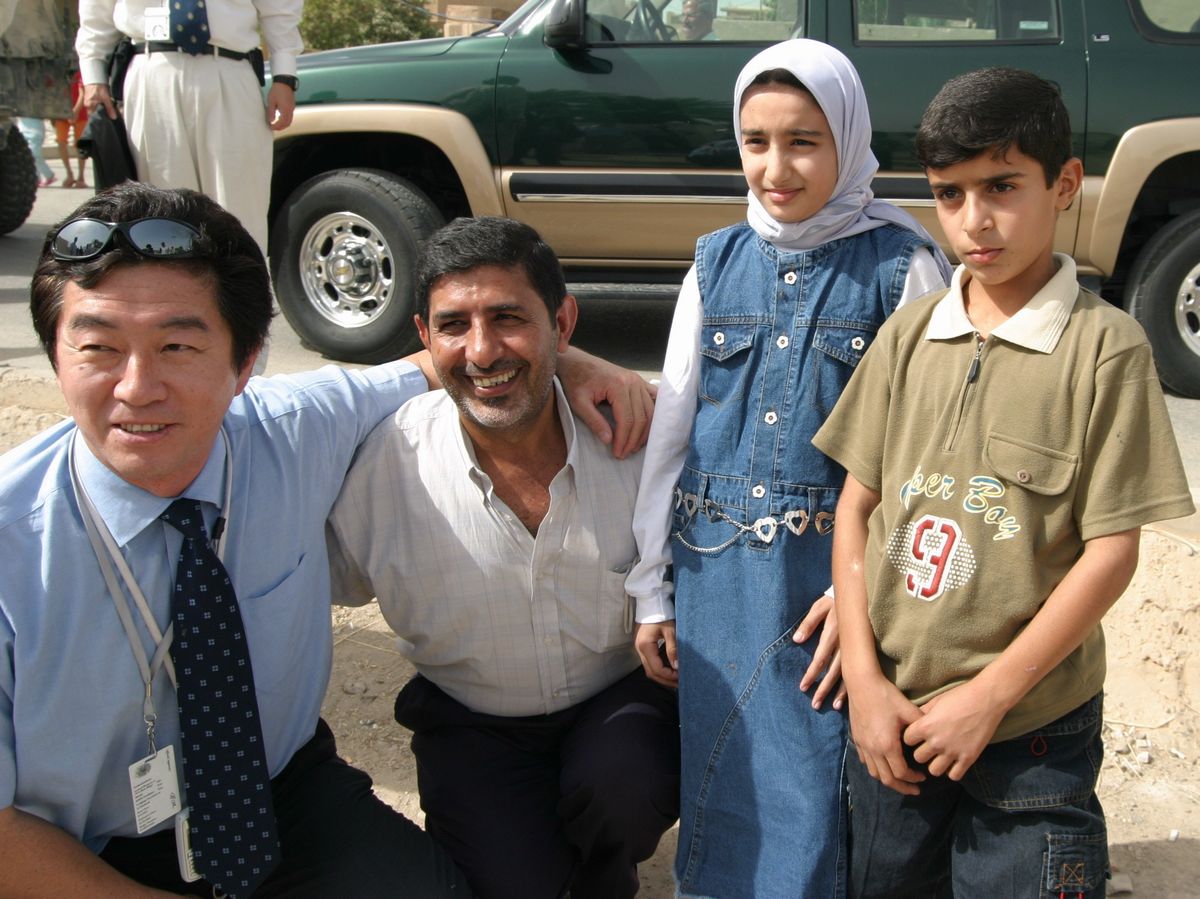 写真・図版 : 2003年、イラクで殺害される2カ月前の日本の外交官・奥克彦さん（左端）。国際支援で再建されたバグダッドの小学校を訪れた＝朝日新聞社