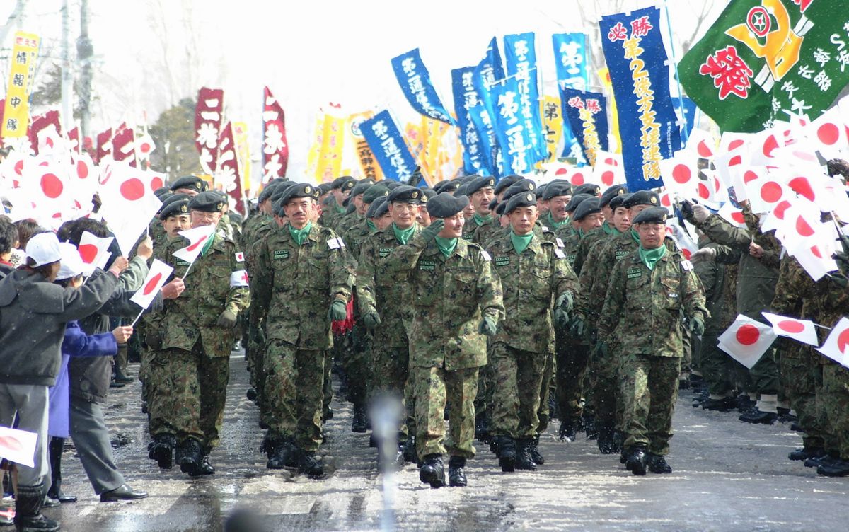 写真・図版 : 2004年、見送りに応えながら行進する陸上自衛隊のイラク派遣隊員＝北海道の陸自旭川駐屯地。朝日新聞社