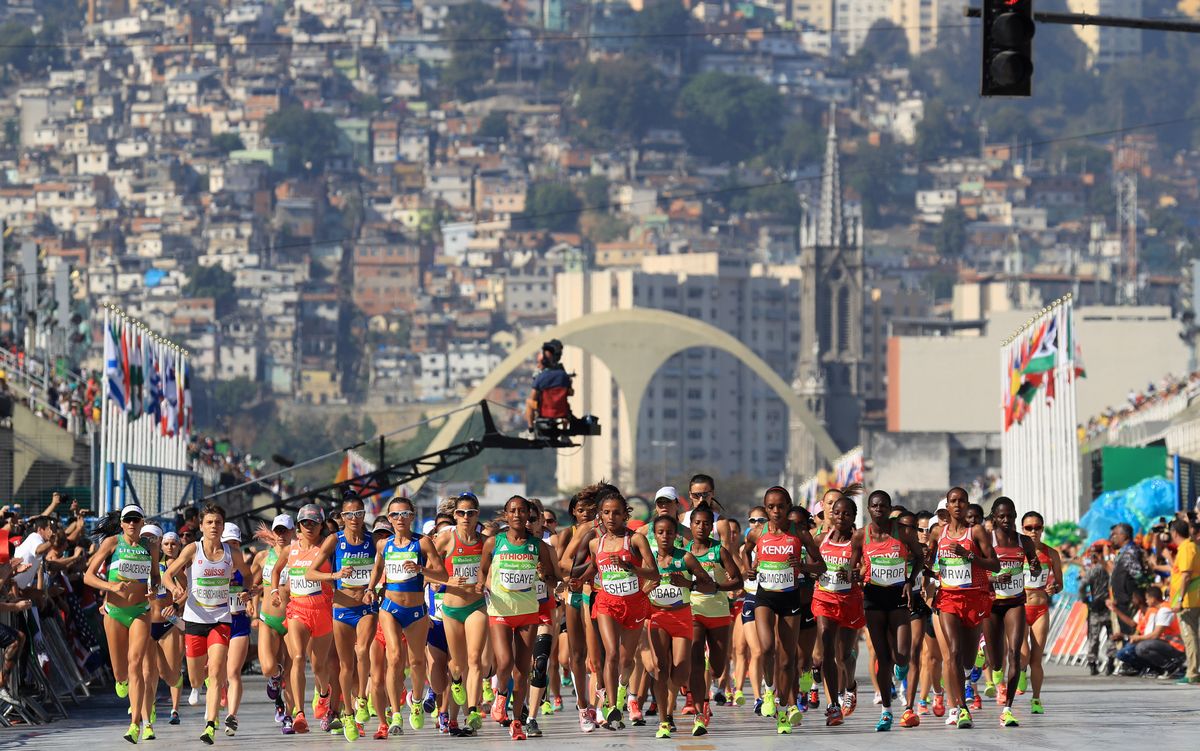 写真・図版 : リオ五輪の女子マラソンで、ファベーラを背にスタートする選手たち＝2016年8月14日