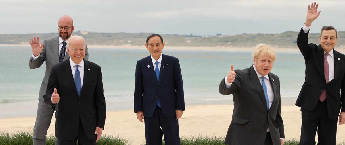 写真・図版 : G7首脳会議で、各国首脳との記念撮影を終え、笑顔を見せる菅義偉首相（中央）。前列左はバイデン米大統領、右は議長のジョンソン英首相＝2021年6月11日、英国・コーンウォール