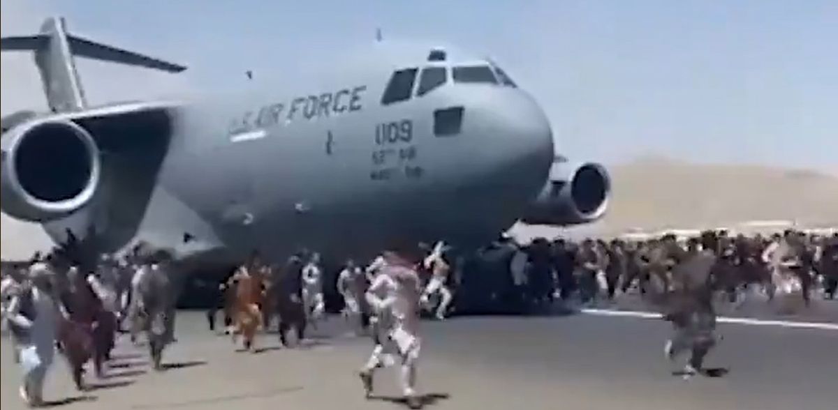 写真・図版 : カブールの国際空港で、米軍機に群がる人々。機体にしがみつく人も多く見られた＝2021年8月16日、衛星放送局アルジャジーラがツイッターに投稿した動画から