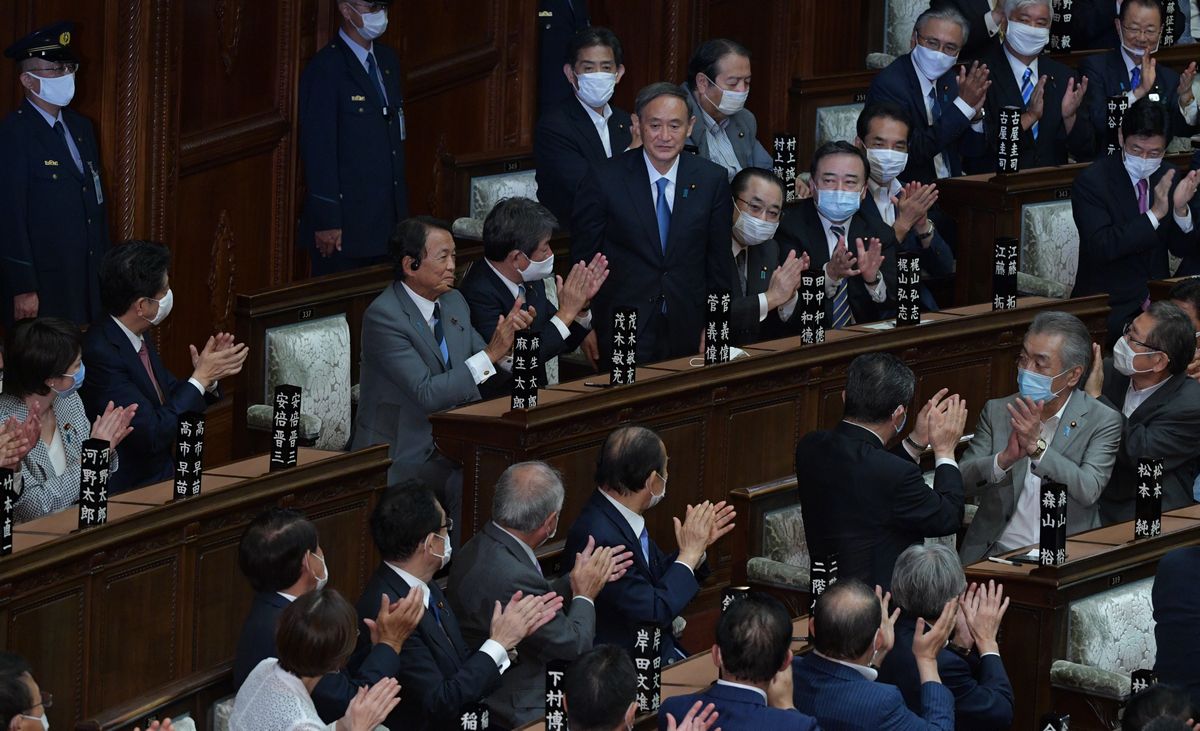 写真・図版 : 衆院本会議で首相指名を受ける菅義偉・自民党総裁。議員からの拍手に笑顔で応えた。左から2人目は安倍晋三首相＝2020年9月16日午後1時45分、国会内