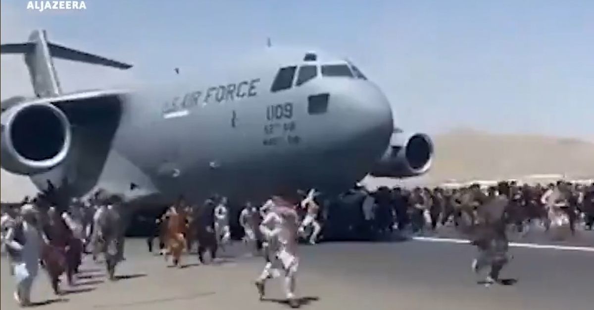 写真・図版 : カブールの国際空港で、米軍機に群がる人々。機体にしがみつく人も多く見られた＝2021年8月16日、衛星放送局アルジャジーラがツイッターに投稿した動画から