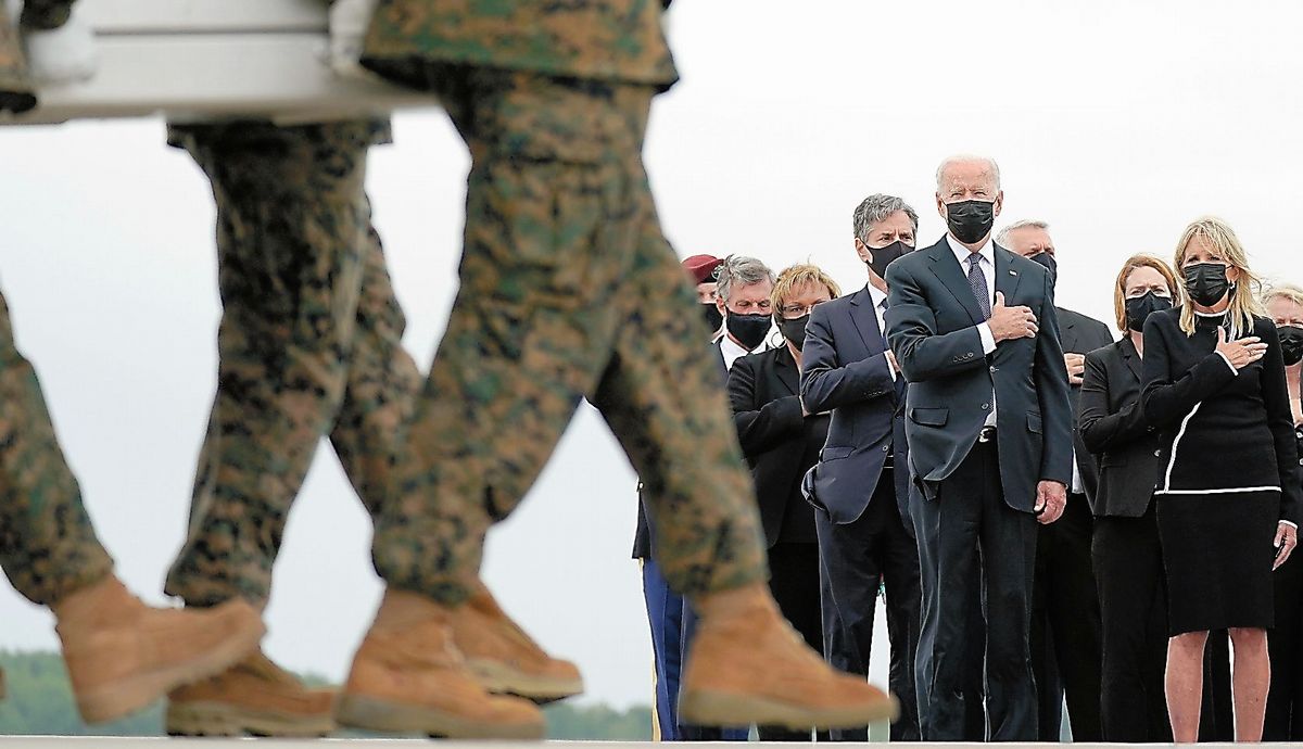 写真・図版 : アフガニスタンでの爆破テロ事件で亡くなった米兵のひつぎを出迎えたバイデン大統領ら=2021年8月29日、米デラウェア州のドーバー空軍基地