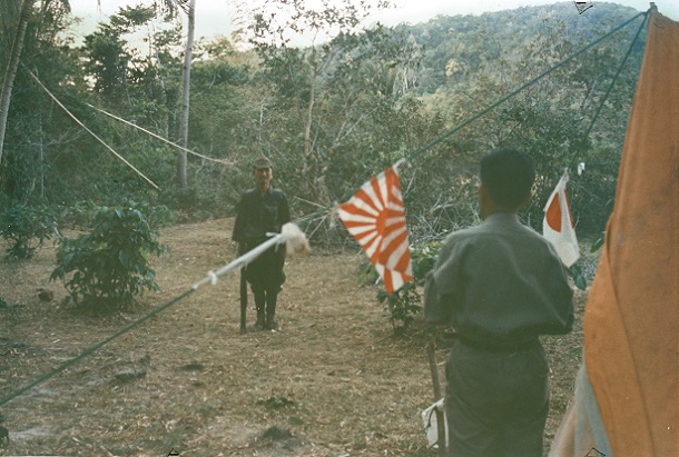 発見者の鈴木紀夫さんと元上官の谷口義美さんのテントの前に姿を現した小野田寛郎さん。直立不動で敬礼し「小野田少尉です。谷口少佐殿の命令に従います」と述べた。52歳になっていた=1974年3月9日午前6時30分、フィリピン・ルバング島