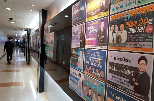 写真・図版 : 多くの塾が入居するビルの廊下には、成績を上げることに定評がある「スター塾講師」たちのポスターが貼られていた＝韓国・ソウル