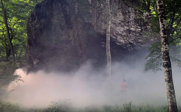 写真・図版 : トム・ミュラー「源泉＜岩、川、起源、水、全長、緊張、間＞」高瀬川の上流から流されたといわれる巨大な仙人岩に、川から汲み上げた水で人工の滝をつくり、霧を発生させ、仙人岩の精神を呼び起こす。Photo: Tsuyoshi Hongo