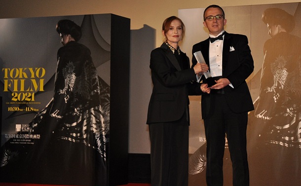 東京国際映画祭のイザベル・ユペール審査委員長(左)が、東京グランプリを受賞した『ヴェラは海の夢を見る』のカルトリナ・クラスニチ監督に代わり登壇したコソボ大使館臨時代理大使にトロフィーを渡した＝2021年1月月8日