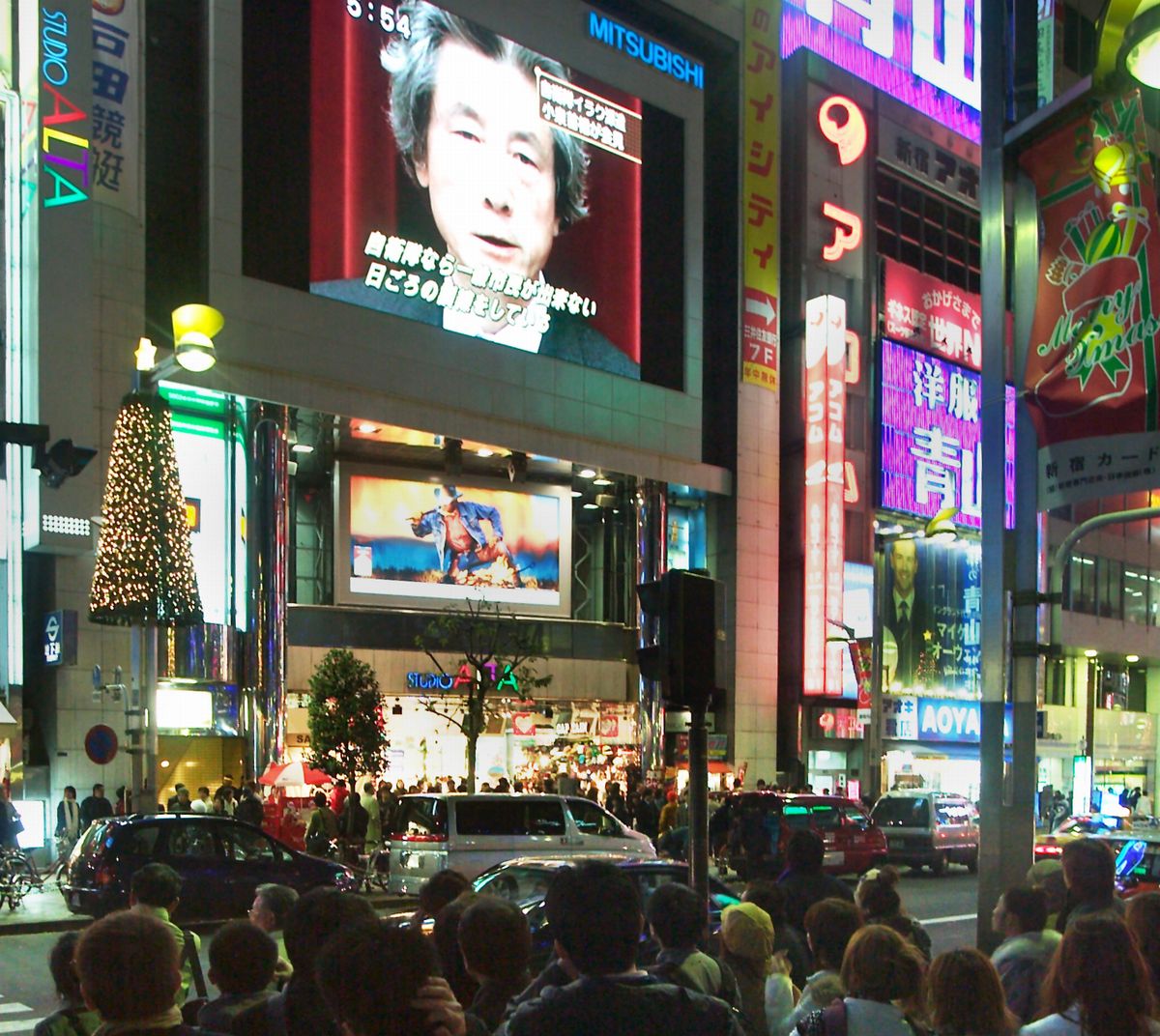 写真・図版 : 新宿駅前の大型ビジョンに、自衛隊のイラク派遣を決めた小泉純一郎首相の会見の様子が映し出された＝2003年12月9日