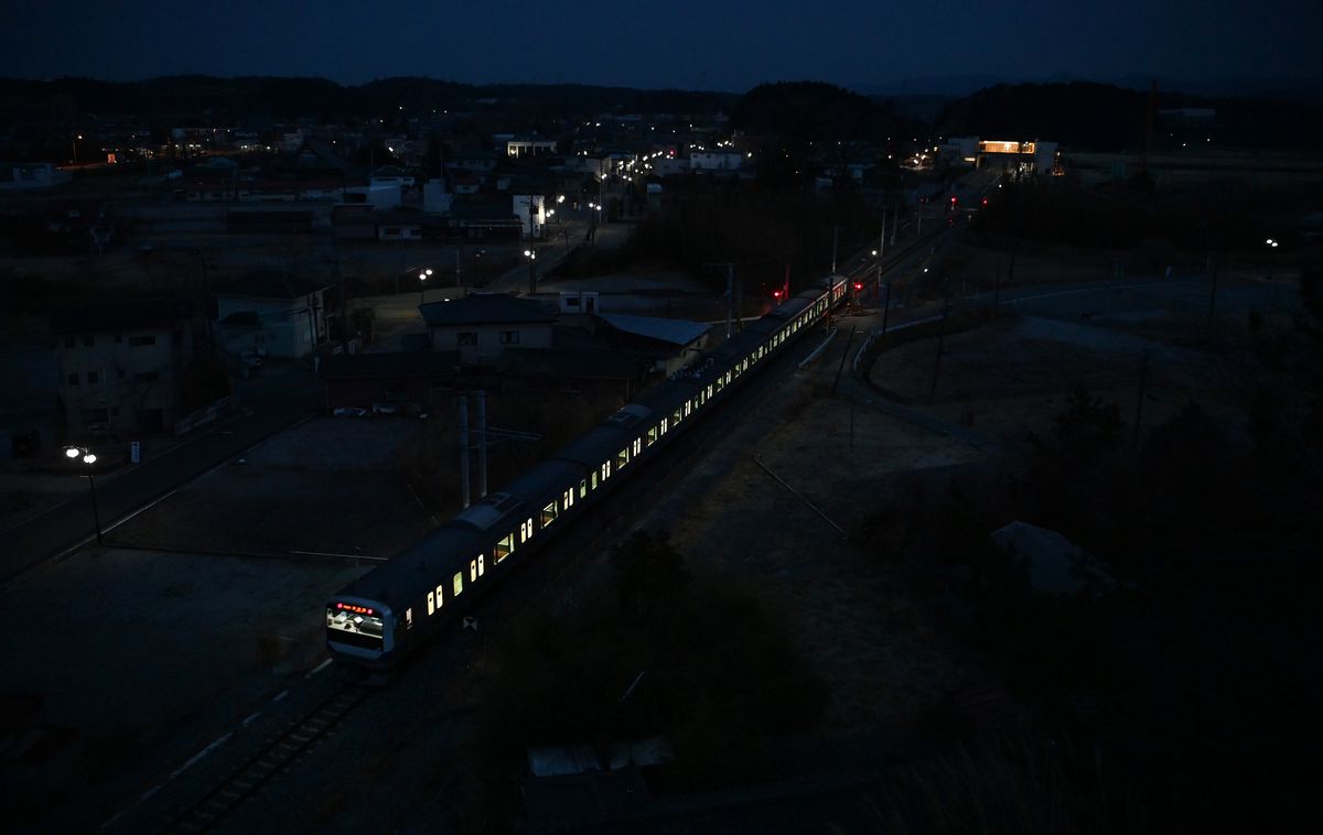 写真・図版 : 建物の解体が進む福島県双葉町の中心部を走る常磐線の上り電車。町はこの区域の来春の避難指示解除を目指している＝2021年3月12日
