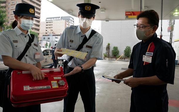 携行缶へガソリンを販売する際、使用目的などを確認するよう指導する消防署員ら＝２０２０年７月１７日、京都市下京区、