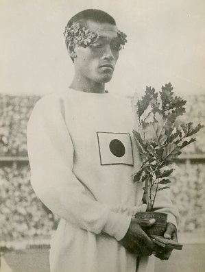 写真・図版 : 1936年ベルリン五輪の男子マラソンで優勝し、表彰台に立つ孫基禎選手。日本統治時代の朝鮮半島出身で、日本代表として日の丸をつけ出場した