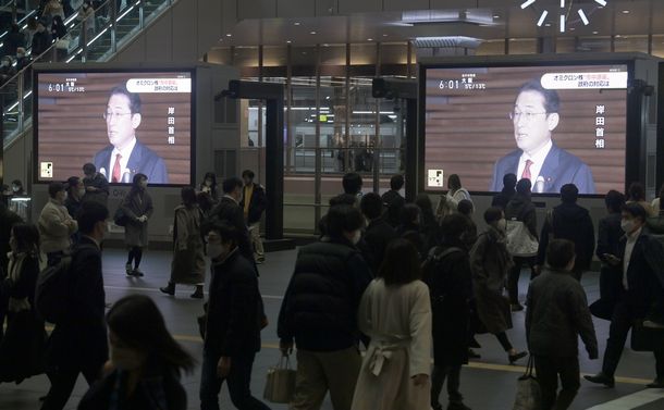 写真・図版 : 岸田文雄首相がオミクロン株の市中感染について会見するニュースが流れる中、帰路につく人たち＝2021年12月22日、大阪市北区