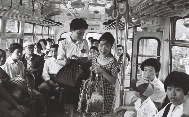 写真・図版 : 混み合うバスの車内、「間に合わない」とどなる客、泣きわめく子供…、どんなに不快指数の高い日でもプンとできないのが車掌をつとめるバスガール車掌の宿命＝1961年9月