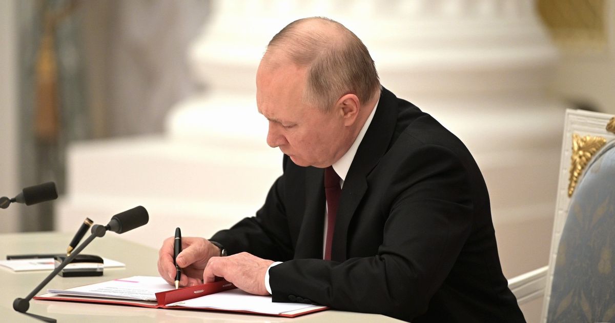 写真・図版 : モスクワで2月21日、「ドネツク人民共和国」と「ルガンスク人民共和国」の独立を承認する大統領令に署名するプーチン大統領。ロシア大統領府が写真を公表した 