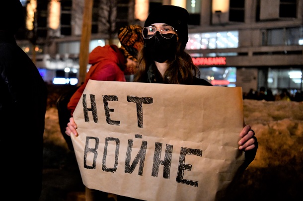写真・図版 : モスクワ中心部の広場で開かれた抗議デモで、「戦争反対」と書かれた紙を掲げる女性。この数十秒後に拘束された＝2022年2月24日
