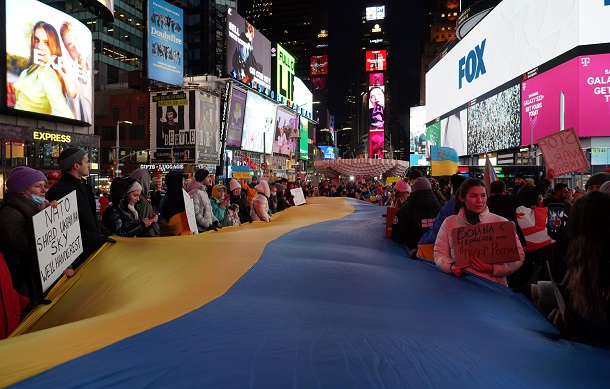 ロシアによるウクライナ侵攻に抗議して、米ニューヨークのタイムズスクエアでウクライナ国旗を広げる人たち=2022年2月25日
