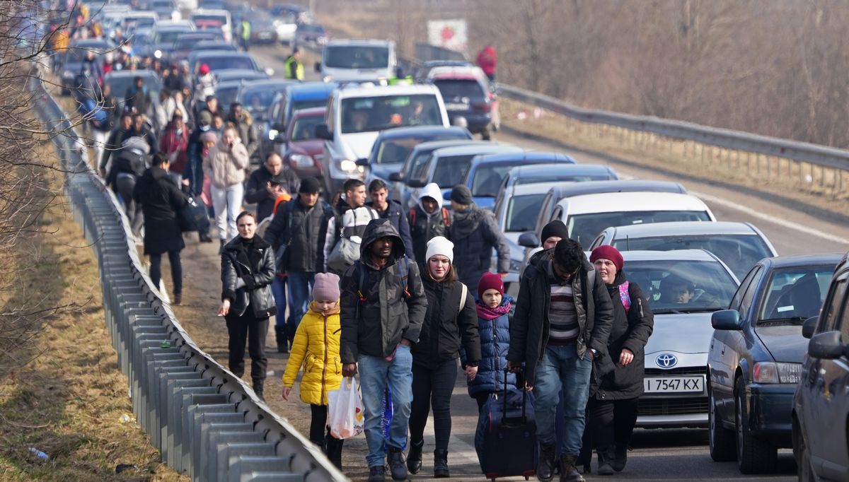 写真・図版 : ウクライナから国外に避難するため、ポーランド国境に向かう人たち＝2022年2月26日、ウクライナ西部・シェヒニ近郊