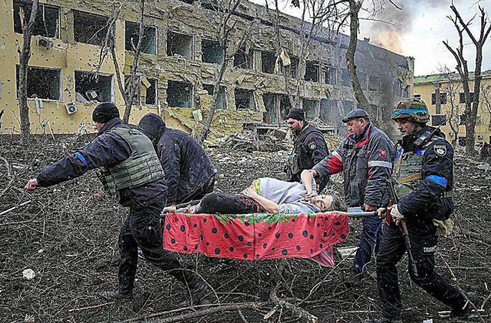 写真・図版 : ウクライナのマリウポリで、ロシア軍の攻撃を受けた産科病院から、負傷して運び出される妊婦＝2022年3月9日