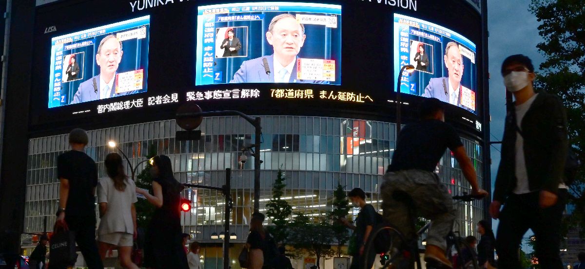 写真・図版 : 緊急事態宣言について会見する菅義偉首相の映像が街頭の大型ビジョンに映し出された＝2021年6月17日、東京都新宿区