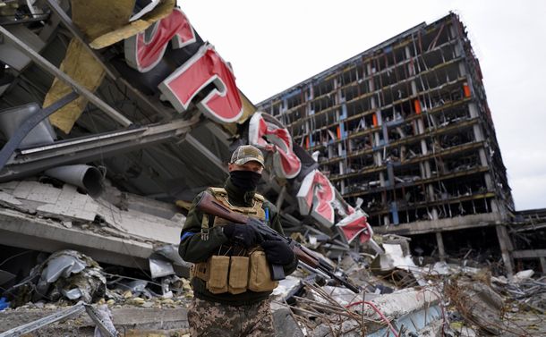 写真・図版 : ロシア軍の攻撃を受け破壊されたショッピングモール前を警備するウクライナ軍兵士＝2022年4月6日、ウクライナ・キーウ