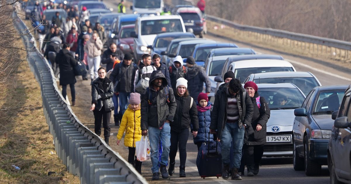 写真・図版 : ポーランド国境に向かう人たち＝2022年2月26日、ウクライナ西部・シェヒニ近郊