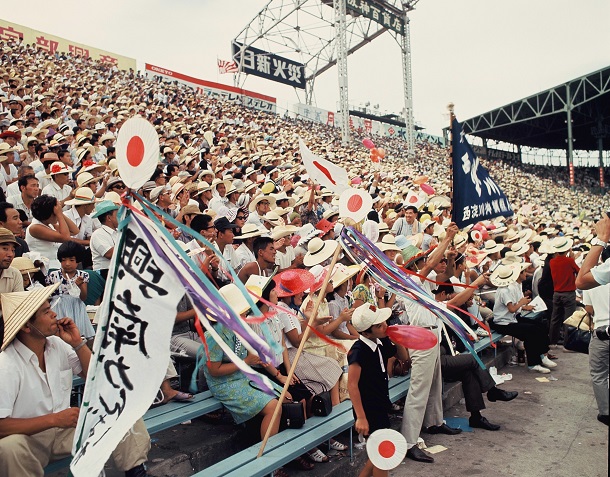 写真・図版 : 「復帰前」の1968年、夏の甲子園大会で声援を送る興南の応援団。日の丸の旗やうちわが目立つ 