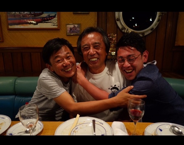 写真・図版 : 沖縄で、在りし日の福田由貴夫カメラマン(左)と筆者(中央)=筆者提供