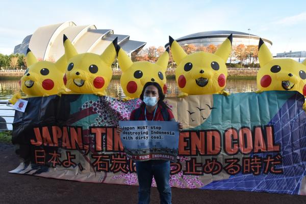 写真・図版 : COP26会場前でピカチュウの着ぐるみを着て、日本が支援する石炭火力発電計画に抗議するNGOのメンバー＝2021年11月、英グラスゴー