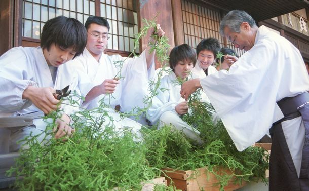 写真・図版 : 新春の神事に使うヒカゲノカズラを結わえる人たち＝京都市の伏見稲荷大社、2001年12月撮影
