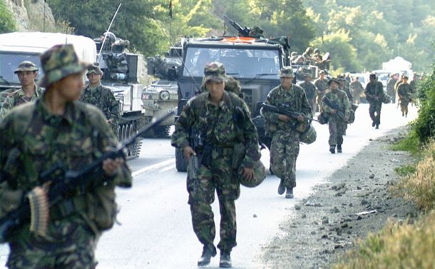 写真・図版 : マケドニア国境を越えてユーゴスラビア・コソボ自治州に入り、幹線道路を警戒しながら進む英軍兵士たち＝1999年6月