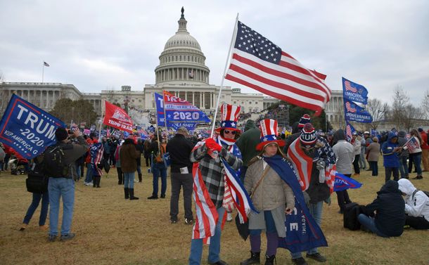 写真・図版 : 米連邦議会議事堂襲撃事件の直後、現場にいたトランプ氏の支持者。帽子には、陰謀集団「QAnon」のスローガンが書かれていた＝2021年1月6日、ワシントン