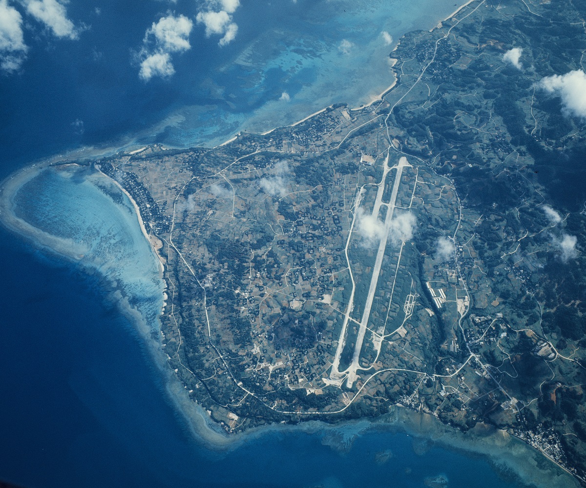 写真・図版 : 1973年5月の沖縄本島の本部半島。中央の滑走路は旧米軍本部飛行場跡で、飛行場左の海岸付近が海洋博予定地＝朝日新聞社機から