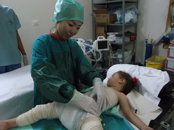 写真・図版 : シリア北部の病院で、ガソリンの引火によるやけどを負った女の子を治療する白川さん＝2013年7月、国境なき医師団提供 