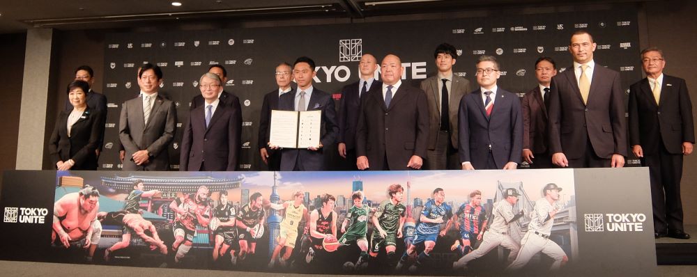 写真・図版 : 「TOKYO UNITE」の記者会見には参加チーム・団体の代表者と小池百合子都知事（前列左端）、室伏広治スポーツ庁長官（同右端）が出席した＝7月7日、都内のホテル