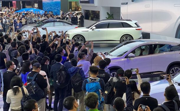 写真・図版 : 電池はEVの中核技術でもある。中国の新興EVメーカーが発表した新型車（中央の白い車）には、多くのメディア関係者らが詰めかけた＝2021年11月、広州