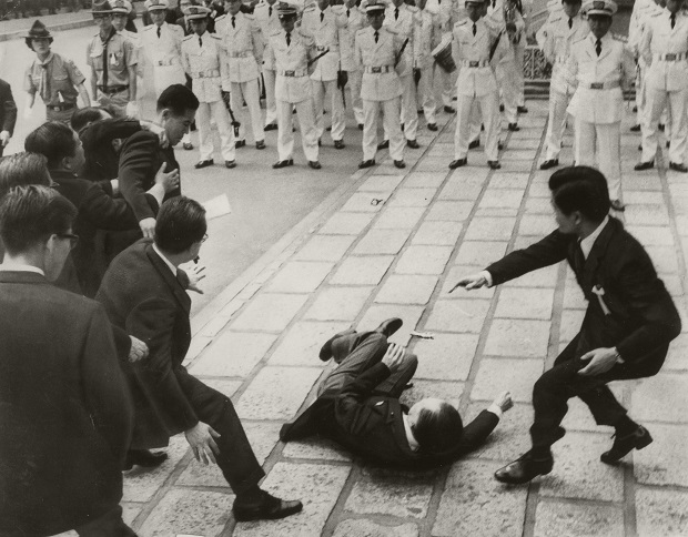 写真・図版 : 佐藤栄作元首相の国民葬式場前で、右翼の男に襲われて倒れた三木首相（当時）。左上部ボーイスカウトの右で、制止されながら首相を見下ろしているのが犯人＝1975年6月16日、東京・北の丸公園の日本武道館前 