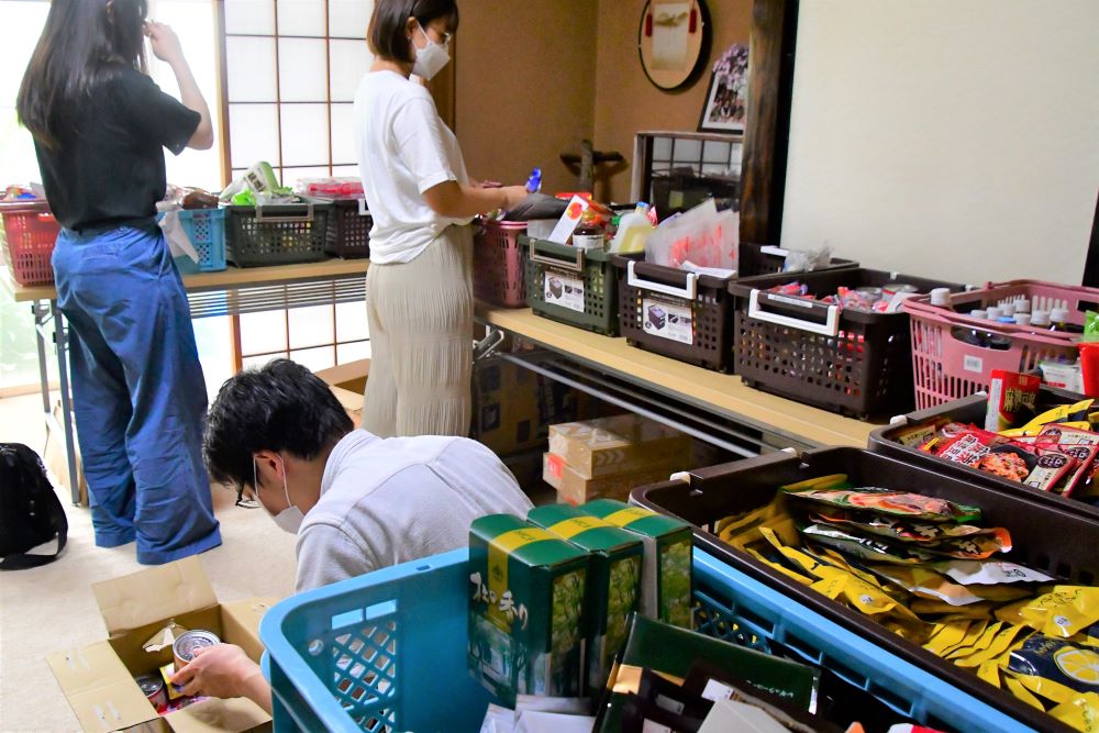 写真・図版 : 生活困窮者に配る食糧を箱に詰めるボランティア＝2021年7月、仙台市