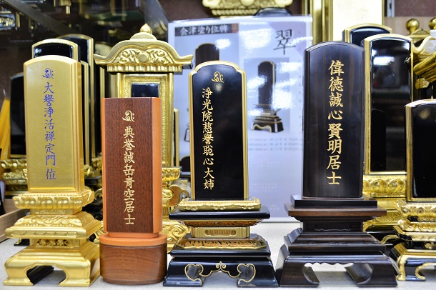 写真・図版 : 仏壇店に並ぶ位牌。戒名が見本として示されている＝大阪市