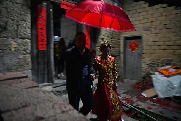 新婦は赤い傘を差した父親に手を引かれて自宅の土楼を出発した。2019年