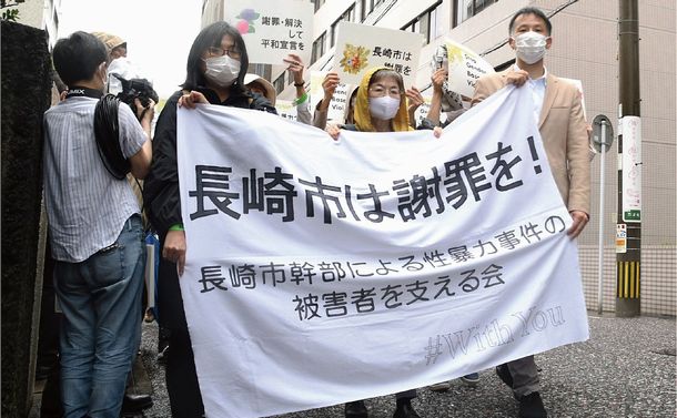 写真・図版 : 判決の日、横断幕を掲げて法廷に入る支援者。左が筆者=2022年5月30日、長崎市