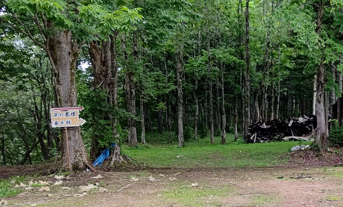 写真・図版 : 木立の中にある「笹の墓標展示館」の案内＝筆者撮影