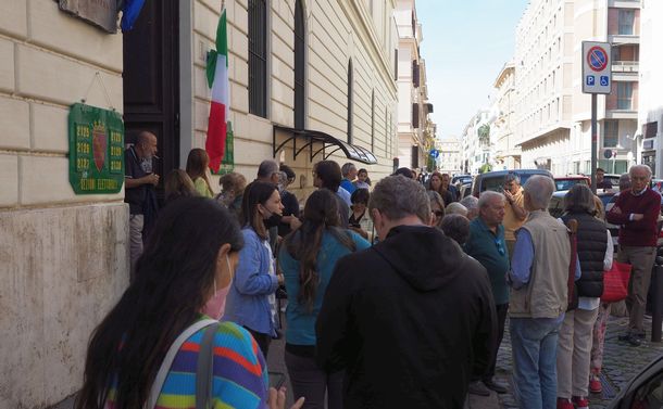 写真・図版 : イタリア総選挙の投票所となった学校の入り口の前に並ぶ有権者。朝から続々と人々が投票に訪れた＝2022年9月25日午前、ローマ