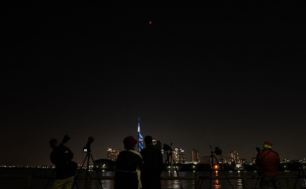 皆既月食を観察したり、撮影したりする人が川沿いに多く並んだ=2022年11月8日午後8時15分