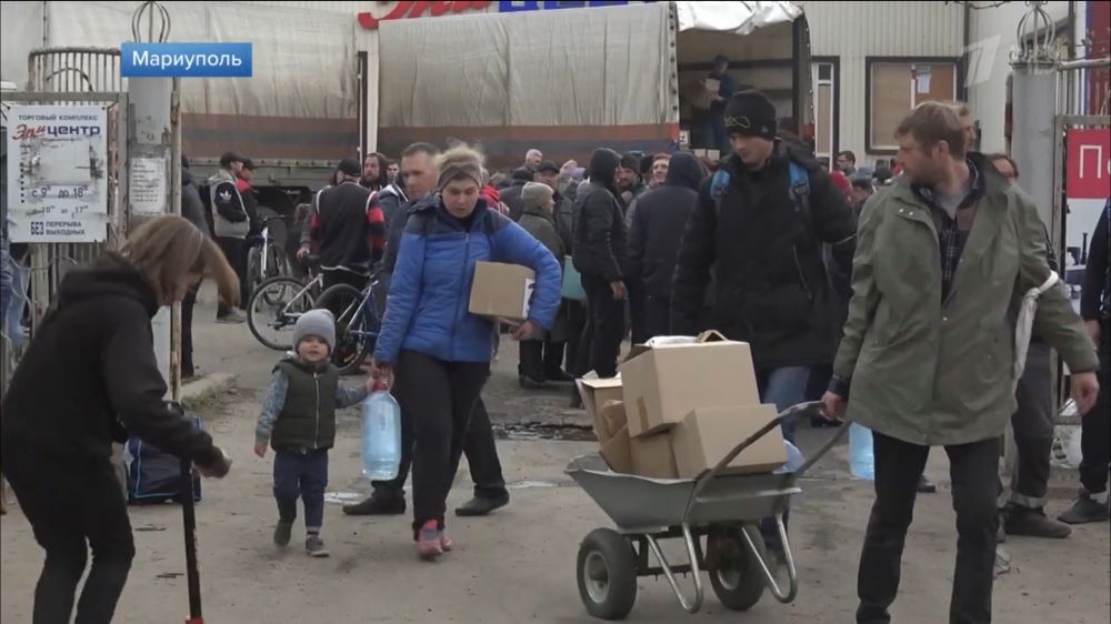 ロシア側が配った食料や水を抱えて歩くウクライナ南東部マリウポリの住人＝ロシア国営テレビの映像から　2022年4月17日
