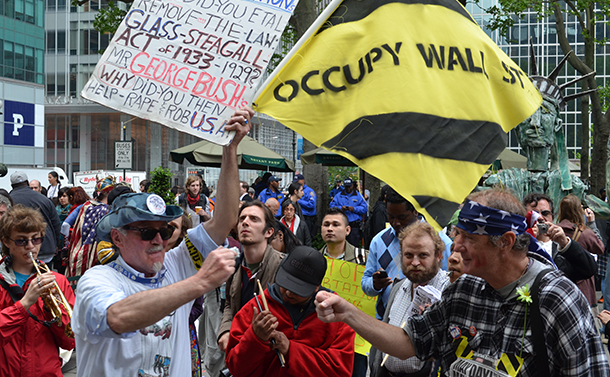 写真・図版 : 「ウォール街を占拠せよ」との旗を掲げるデモ参加者たち=2012年5月、米ニューヨーク