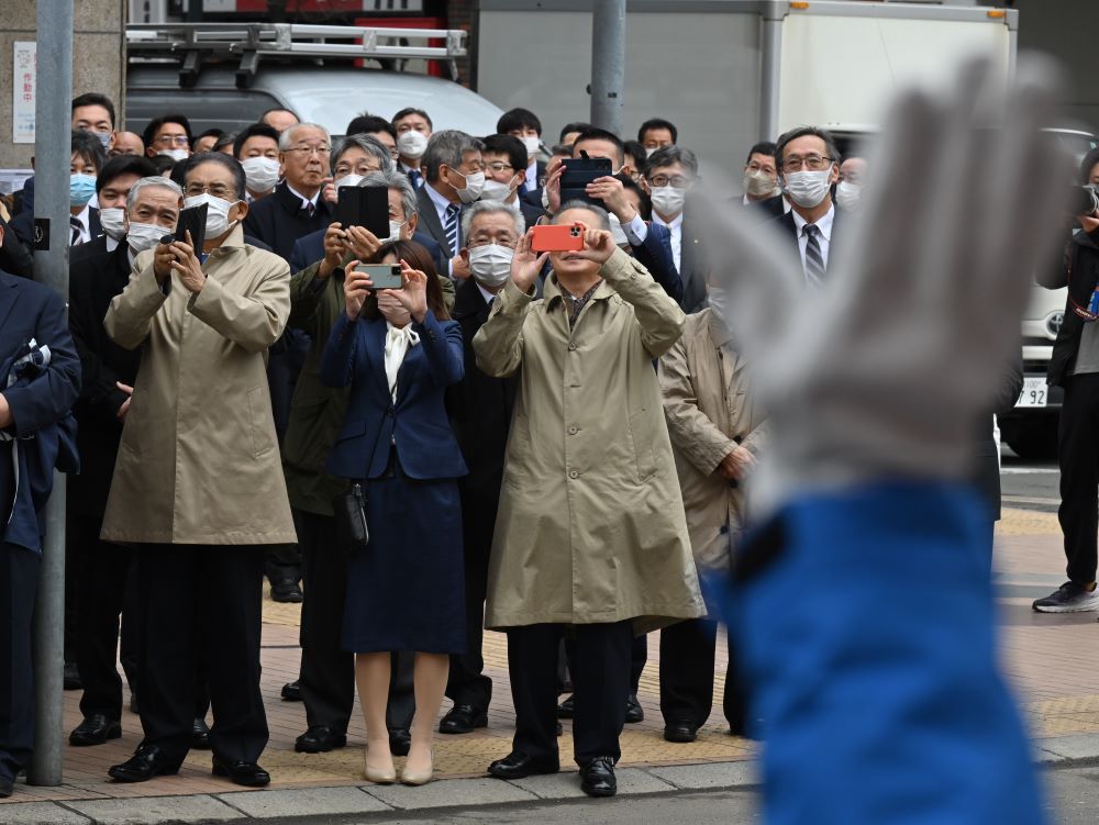 支援者が手を振る中、候補者の第一声を聞く人たち＝２０２３年３月２３日午前９時２９分、札幌市、角野貴之撮影