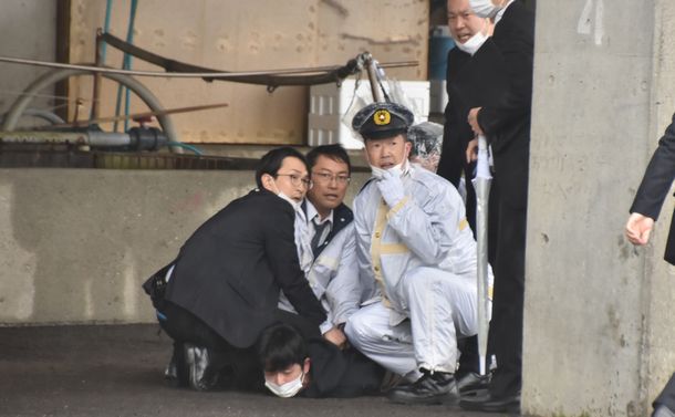 写真・図版 : 筒状の物体を投げた木村容疑者を取り押さえる警察官ら＝2023年4月15日、和歌山市の雑賀崎漁港